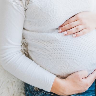 Eine schwangere Frau hält sich den Bauch.